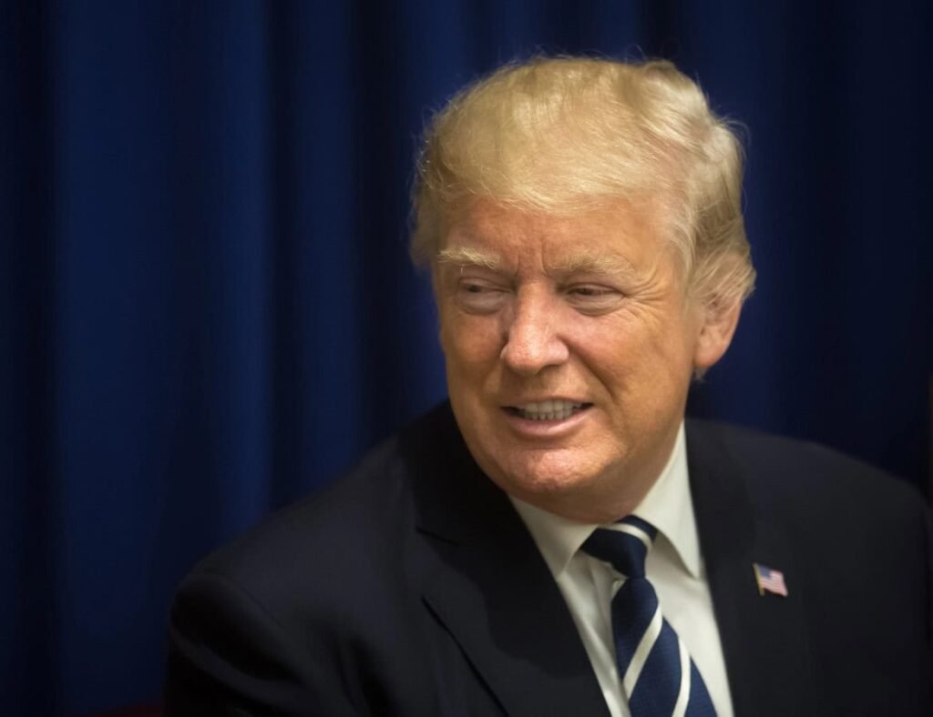 Older graduate student standing near bookshelf