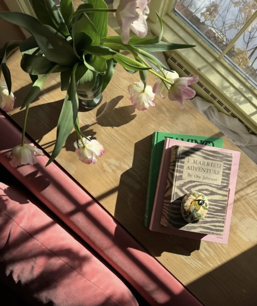 Idun St Paul with white walls, a clothing rack, perfumes, and plants in front of a large window