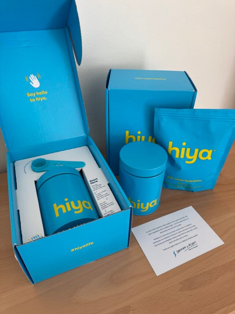 A set of blue hiya-branded hydration products, including a bottle, canister, and pouch, arranged on a wooden surface with blue packaging and an informational card.