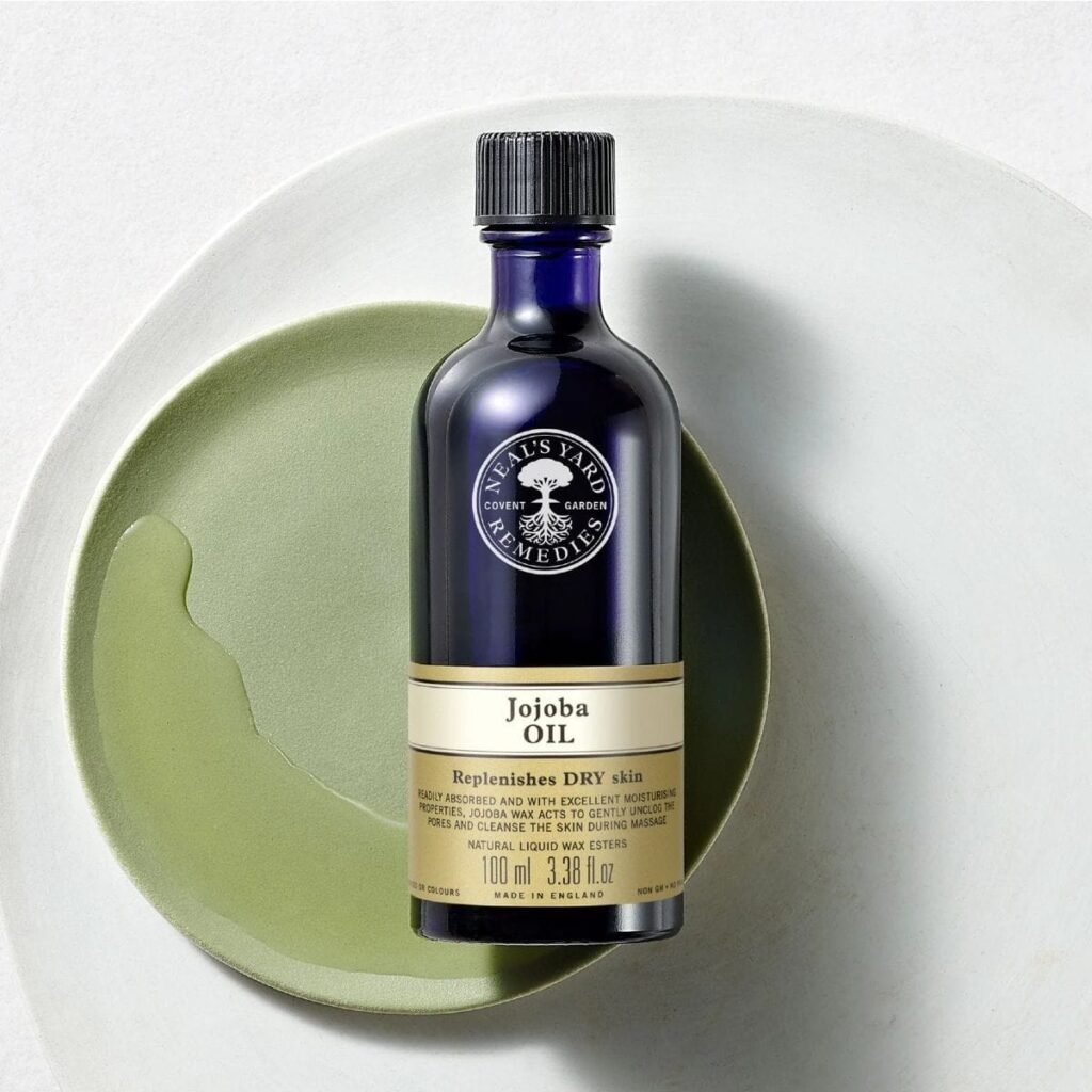 Blue glass bottle of jojoba oil from Neal's Yard, on a green plate