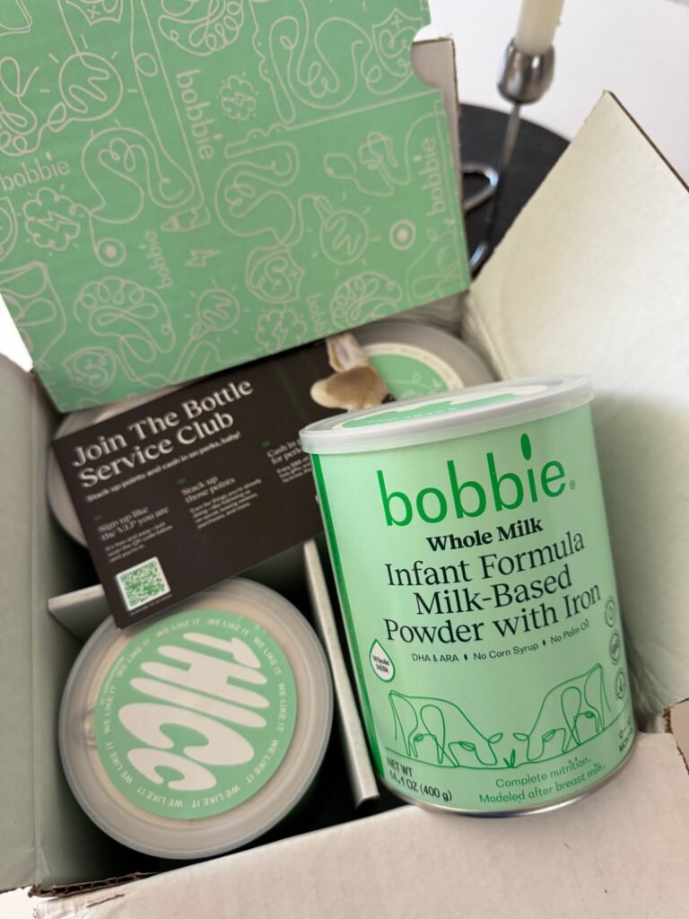 8 Organic Baby Formula Brands We Trust (2026) An open box containing cans of Bobbie Whole Milk Infant Formula Powder and informational card, with the packaging featuring light green branding.